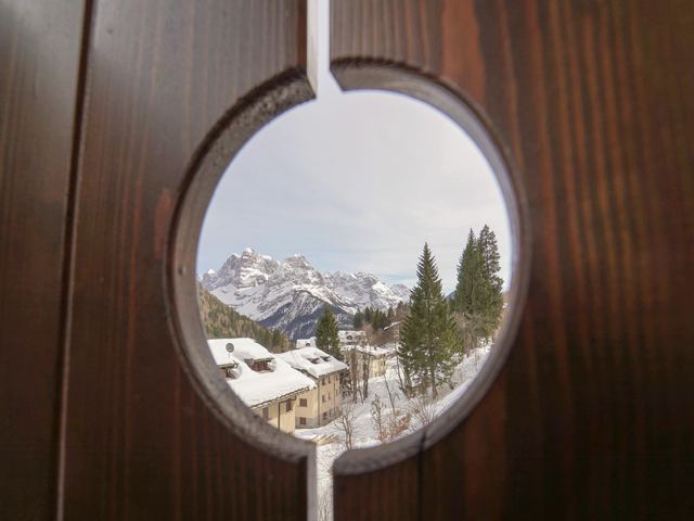 Scorcio delle Dolomiti visto da un oblò in legno della camera